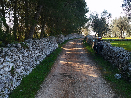 Bicicletta all'ombra tra muri in pietra